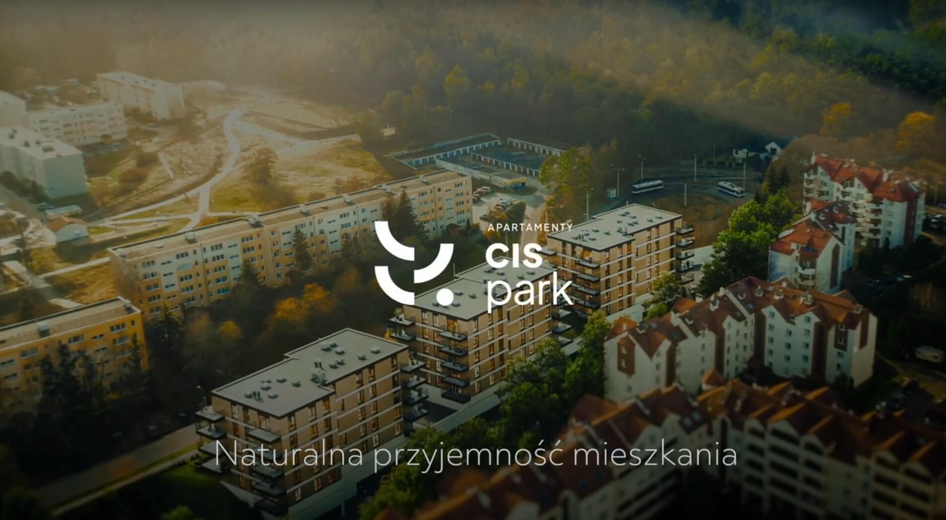 Widok z lotu ptaka na dzielnicę mieszkaniową z nowoczesnymi apartamentowcami otoczonymi bujną zielenią, z logo „CIS Park” i podpisem „Naturalna przyjemność mieszkań”.