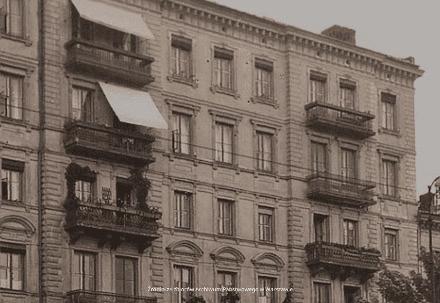 Sepiowa fotografia zabytkowego, wielopiętrowego budynku z dużymi oknami i kilkoma balkonami w Warszawie, prezentująca ozdobne detale architektoniczne. Kilka markiz rozciąga się od balkonów, wskazując na zamieszkane mieszkania.